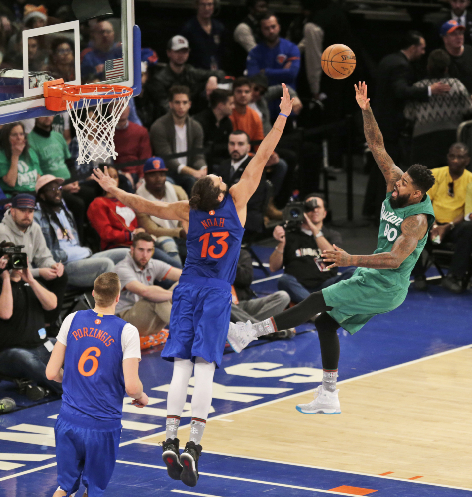 Boston's Amir Johnson, right, puts up a shot over New York Knicks' Joakim Noah (13) during the second half Sunday in New York.
