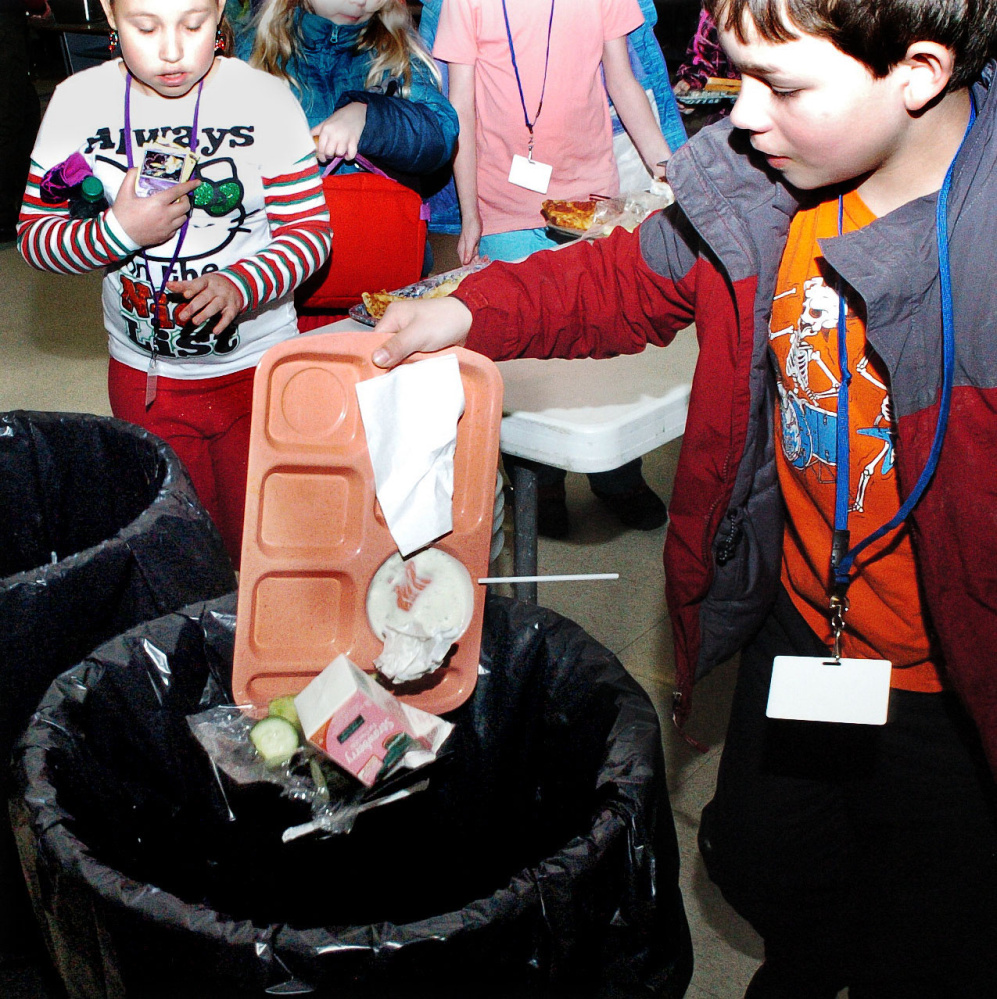 Winslow Elementary School student Aidan Giguere and others students empty food into trash cans in the school cafeteria on Wednesday. Starting Jan. 3, the school will pilot a food-waste recycling program that involves the Agri-Cycle Energy processing plant in Exeter.