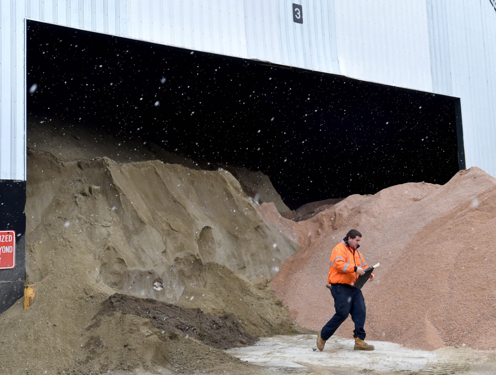 Bobby Bellows removes a piece of trash from the sand and salt piles at the Waterville Public Works yard in Waterville on Thursday, as a Nor'easter moved into the region.