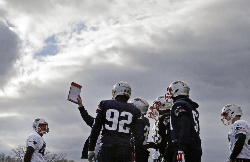 New England Patriots defensive players huddle to look at a playbook during practice Wednesday in Foxborough, Mass. The Patriots boast one of the best defenses in the National Football League this season.