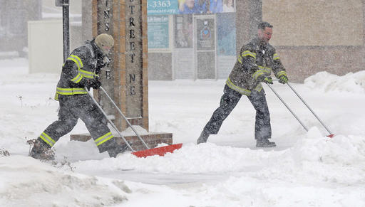Firefighters Shane Weltikol, left, and Chad Nicklos clear snow in downtown Mandan, N.D., on Sunday. 
The Bismarck Tribune/Tom Stromme
