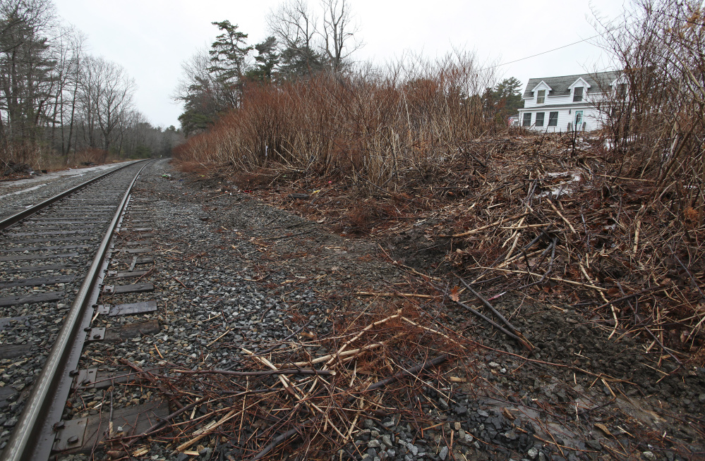 Carson Filiault accidentally backed over an embankment near his apartment, at right, on Wednesday and ended up on the train tracks just as a Downeaster was approaching.