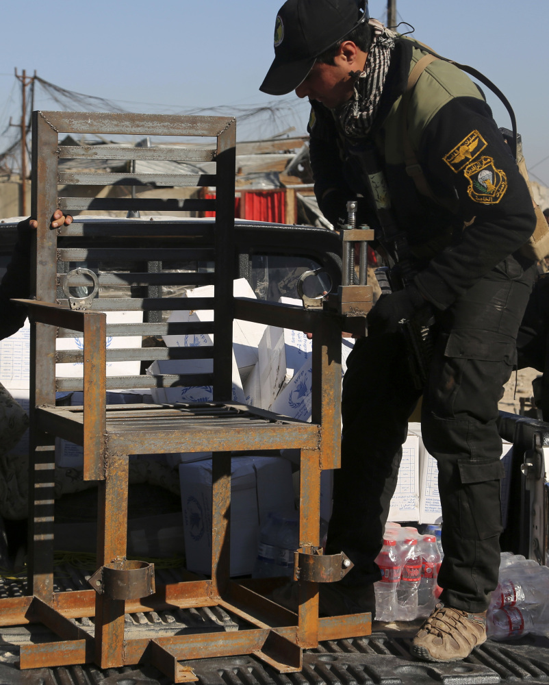Iraqi special forces display a chair they say militants used to torture people, found in a detention facility.