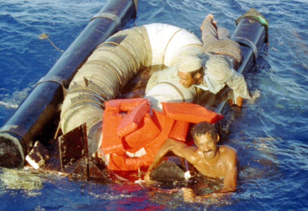 Refugees cling to their overturned raft in 1994 as the Coast Guard cutter Chandeleur moves in to pick them up north of Cuba. Cubans arriving by water have been favored by immigration policy since 1995.