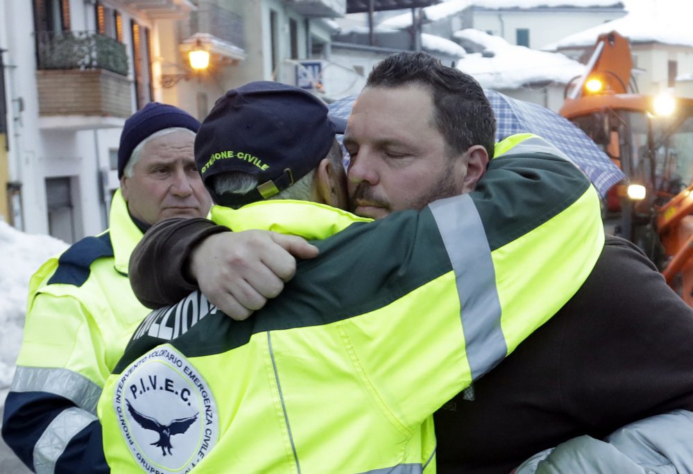 Massimiliano Giancaterino, right, the brother of a victim of the avalanche which buried the Hotel Rigopiano, is hugged by an Italian Civil Protection volunteer Sunday.