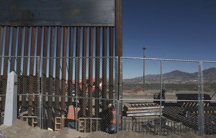 Workers continue work raising a taller fence in the Mexico-U.S. border area separating the towns of Anapra, Mexico, and Sunland Park, New Mexico, on Wednesday. U.S. President Trump signed a directive Wednesday to begin construction on a new border wall.