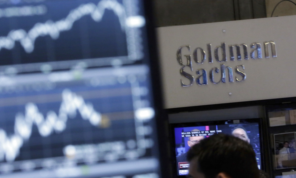 A screen at a trading post on the floor of the New York Stock Exchange is juxtaposed with the Goldman Sachs booth. The Dow climbed to the 20,000 mark because of three stocks.