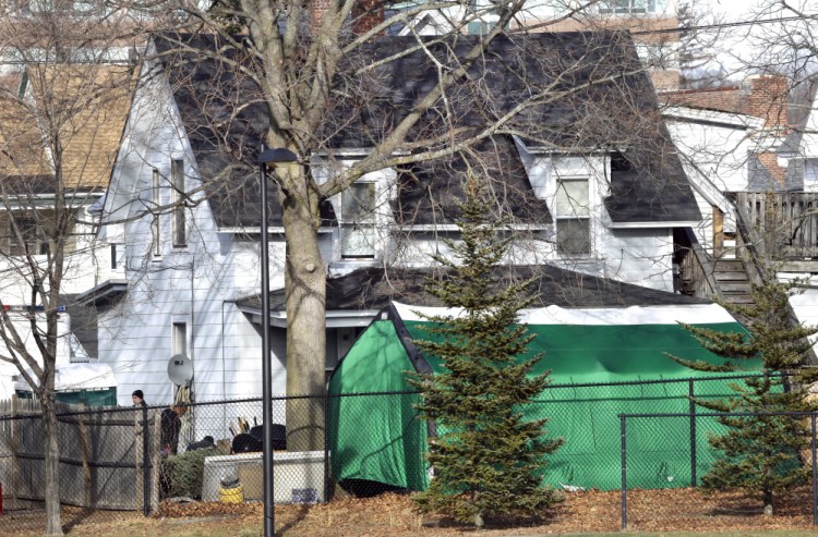 Officials search for clues in a missing person's case behind at tent last week  in the back of a house in Manchester, N.H. The case is linked to four bodies found between 1985 and 2000.