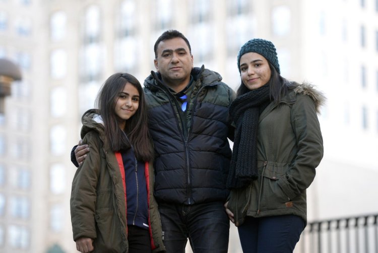 Labed Alalhanfy 49, an Iraqi refugee, with his daughters Omaima 13, left, and Jumana, 19, in Portland's Monument Square on Saturday. They're waiting anxiously to find out whether a third daughter, 20-year-old Bananh, can come to the United States.