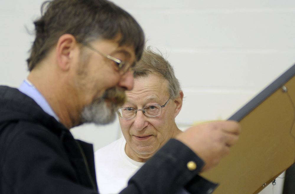 Antique dealer Julian Katz, right, watches Mike Lokuta examine a photograph in Katz' booth during the antique show Sunday in Augusta.