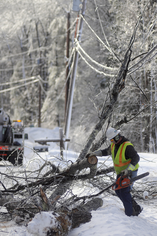 Central Maine Power Co. lineman Sam Pottle cuts a tree that fell on a power line Wednesday in Wayne.