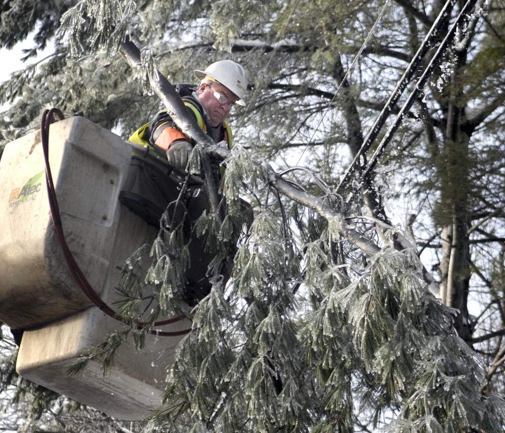 Central Maine Power Co. lineman Wayne Piper removes a limb from a power line Wednesday in Manchester.