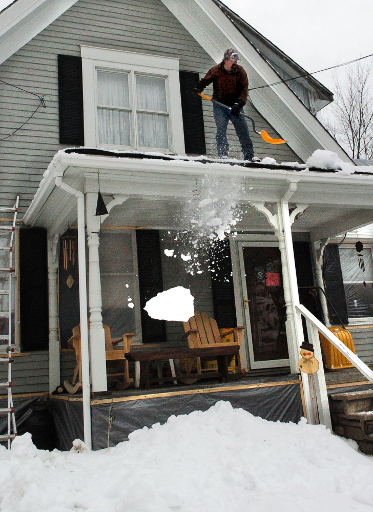 David Austin shovels snow from the roof of a friend's home Tuesday in Fairfield.