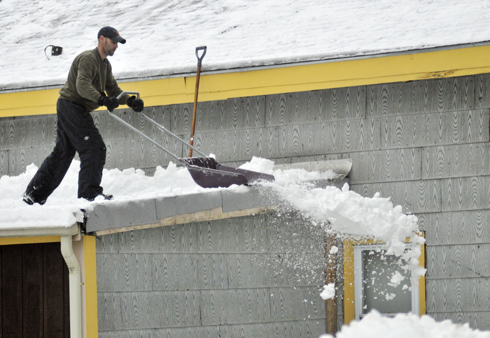 Michael Vachon shovels a roof Feb. 16, 2016, after an overnight snowstorm in Augusta. Vachon said he wanted to get weight off the building after a storm dumped several inches of snow, followed by freezing rain and rain.