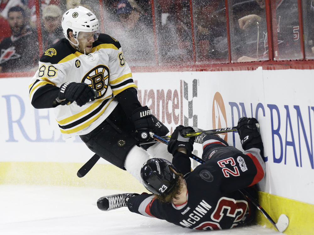 Boston Bruins' Kevan Miller (86) and Carolina's Brock McGinn collide while chasing the puck during the second period Sunday.