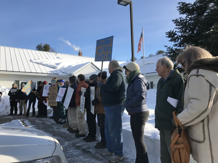 Protesters line up in the cold Monday before submitting a petition at the Augusta office of Sen. Angus King, independent of Maine, asking him to reject the cabinet picks of President-elect Donald Trump.