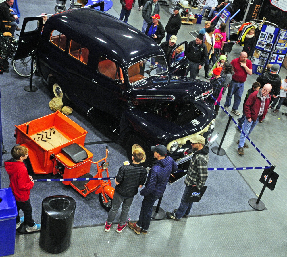 Staff photo by Joe Phelan 
 People look at vehicles on display in the PEP Classic Car Company booth during the Northeast Motorsports Expo on Saturday at the Augusta Civic Center.