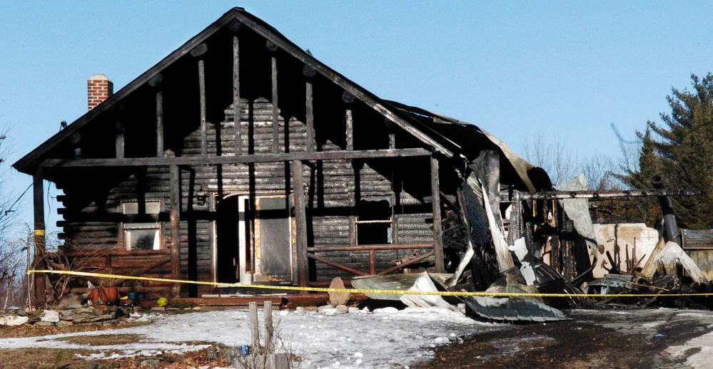 On Sunday, police tape surrounds a burned log home at 1178 China Road in Winslow that was destroyed by fire last Friday.
