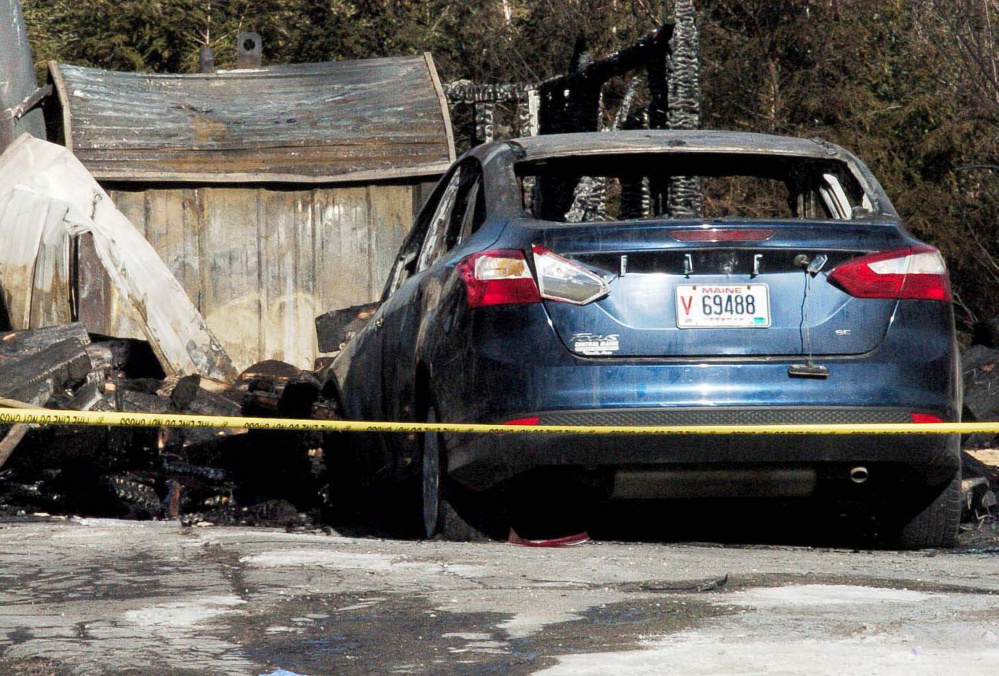 On Sunday police tape surrounds a burned garage and vehicle that were destroyed by fire along with the log home at 1178 China Road in Winslow last Friday.