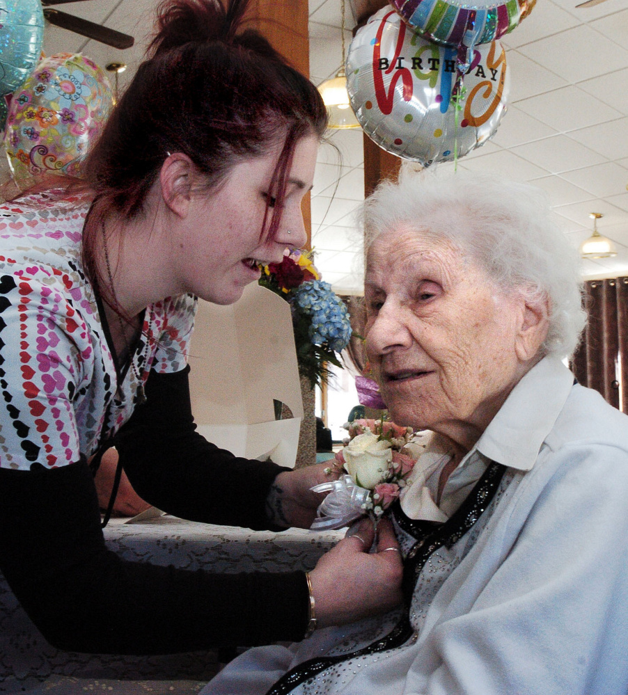 Hillary Dillingham pins a corsage on Ann Labin prior to her 100th birthday party at the Maple Crest Home in Madison on Monday.