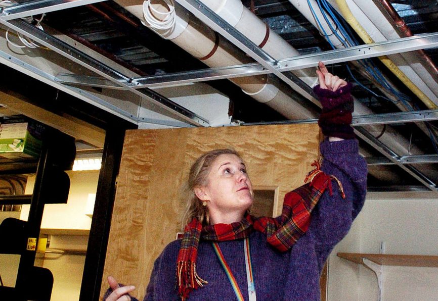 Waterville Public Library Director Sarah Sugden points to a water pipe below a drop ceiling on Dec. 19 that broke and flooded the library building and books. The library plans to close Jan. 25-31 to complete reconstruction from sustained water damage.