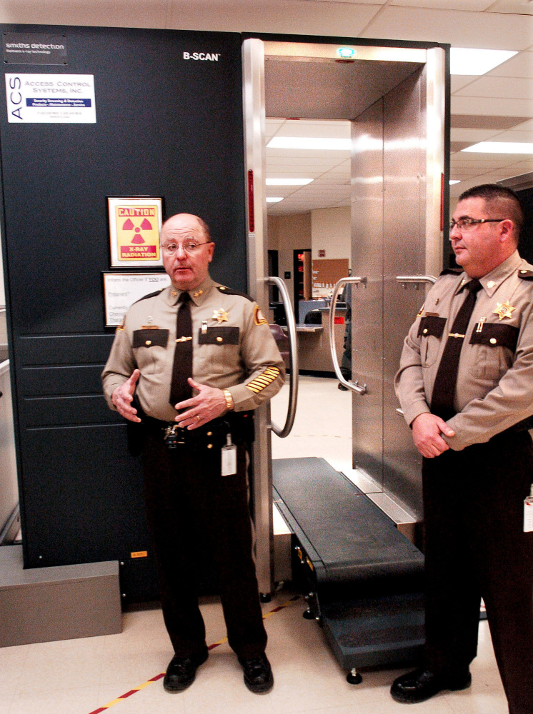 Somerset County Sheriff Dale Lancaster, left, and Somerset Jail Administrator Cory Swope discuss a new body scanner Thursday at the intake department at the East Madison jail. When an inmate gets on the conveyor belt, the scanner can detect objects that the inmate might be concealing inside his or her body in an effort to smuggle them into the jail.
