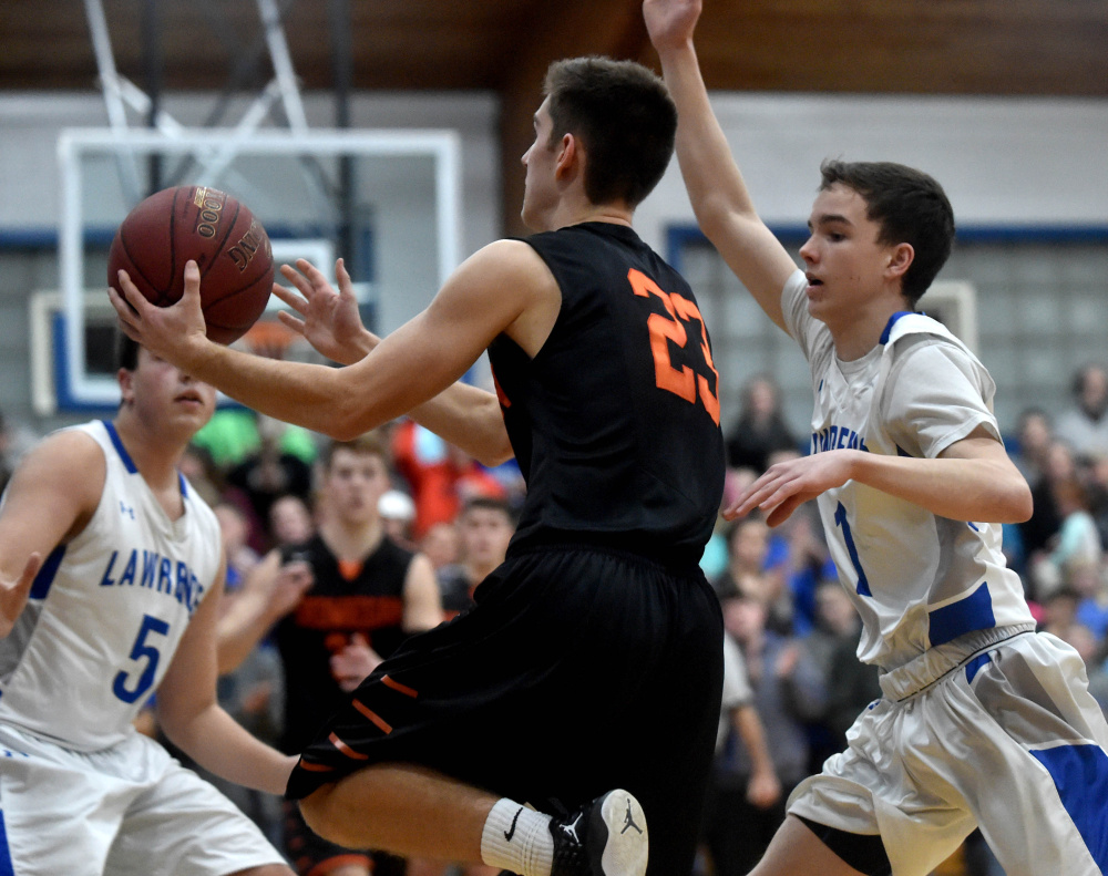 Skowhegan senior captain Brendan Curran, middle, drives to the hoop as Lawrence's Kobe Nadeau defends during a Kennebec Valley Athletic Conference Class A game  Friday night in Fairfield.