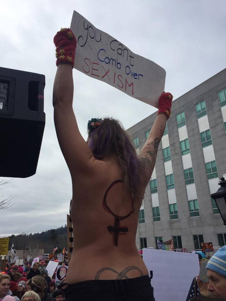 When Capitol Police tried to get this topless woman to step down from a pillar on Saturday at the Women's March on Maine rally in Augusta, the officer was bitten on the hand by another woman, police said.