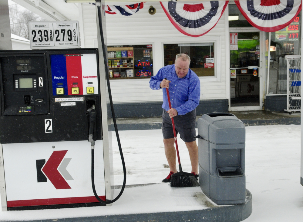 Bob Lippert sweeps snow from around the gas pumps at Easy Mart on State Street in Augusta on Tuesday.