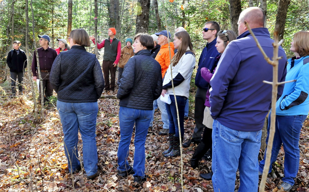 Dylan Dillaway, center, chairman of the Sebasticook Regional Land Trust's Board of Directors, leads two dozen people through a marked trail during a dedication of Cob's Trail in the Kanokolus Bog Prerserve  in Unity on Oct. 19, 2014.