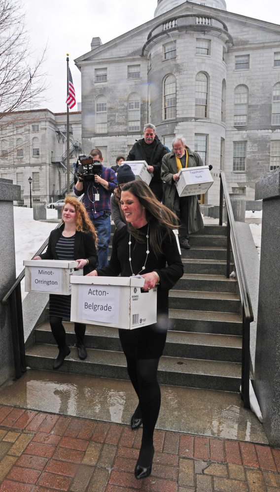 Supporters carry boxes of petition signatures Wednesday in Augusta from the Maine State House to the secretary of state's office in the Cross State Office Building.