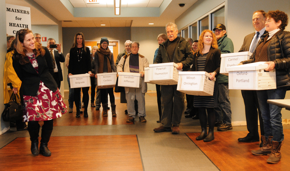 Robyn Merrill, executive director of Maine Equal Justice Partners, far left, talks on Wednesday to MaineCare referendum supporters who carried boxes of petition signatures into the secretary of state's office.