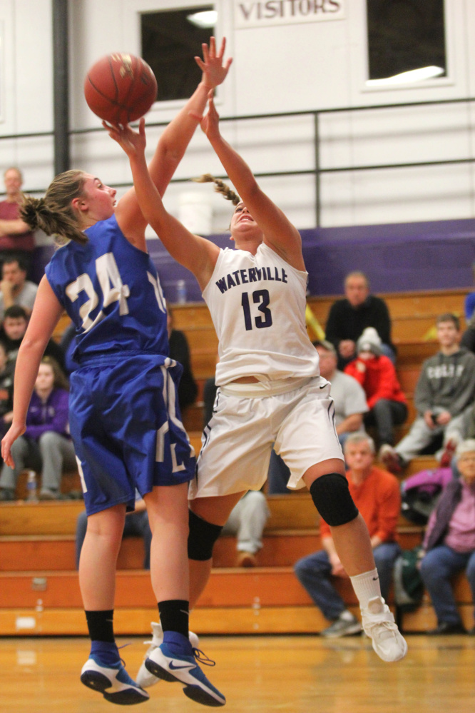 Waterville's Mackenzie St. Pierre, right, puts up a shot over the outstretched arm of Lawrence's Molly Folsom during first-half action Wednesday in Waterville.