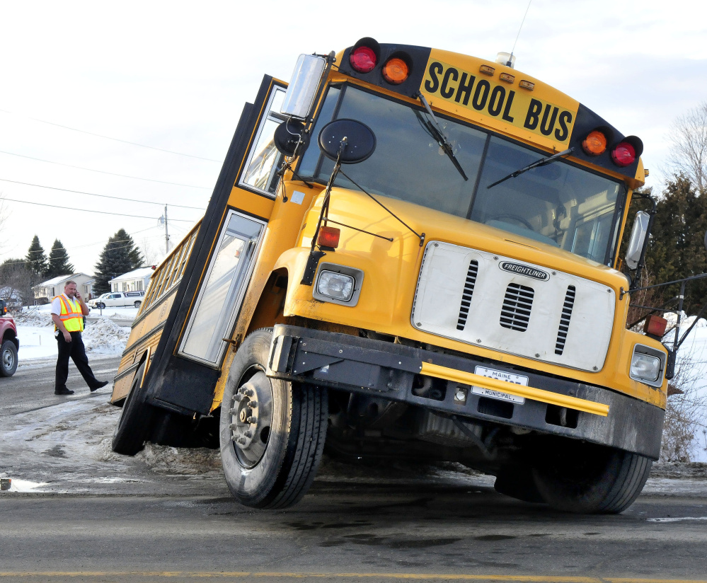 An investigator surveys the scene Thursday after a Winslow school bus ended up in a ditch and became stuck at the corner of Danielle and Benton avenues in Benton.