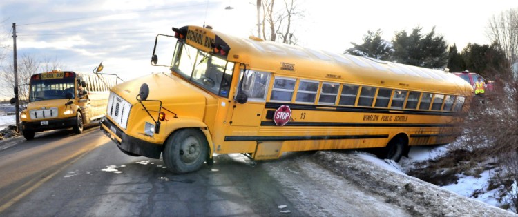A school bus, at left, passes the scene where a Winslow school bus ended up in a ditch Thursday and became stuck at the corner of Danielle and Benton avenues in Benton. No injuries to the driver or the children on the bus were reported in the accident, which left one wheel of the bus in the air.