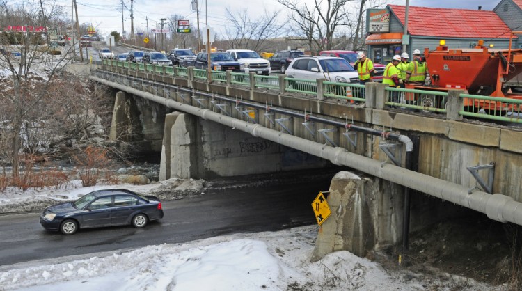This Friday photo shows the Bridge Street Bridge over Cobbosseecontee Stream in Gardiner, where work is scheduled to take place in 2019. The Maine Department of Transportation workers, at right, were there filling in potholes.