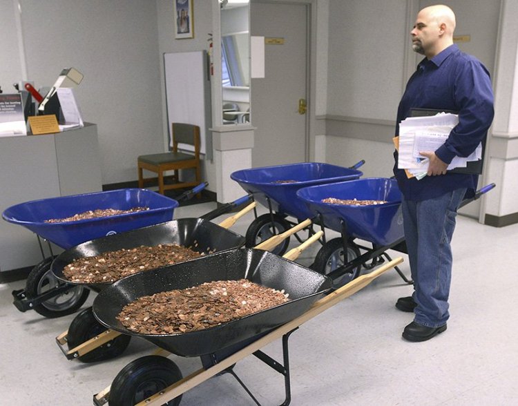 Nick Stafford waits for his number to be called  as he stands beside of 5 wheelbarrows full of change, mostly pennies, at the DMV in Lebanon, Va. 