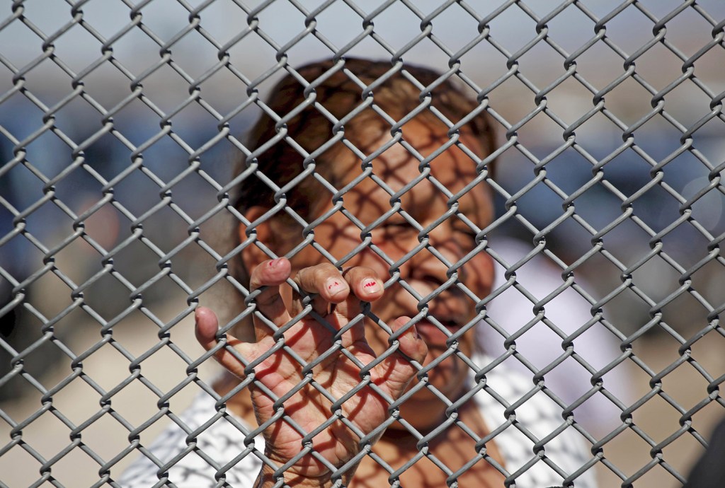 A Mexican migrant talks to a family member through the border fence between Ciudad Juarez and El Paso, Texas.