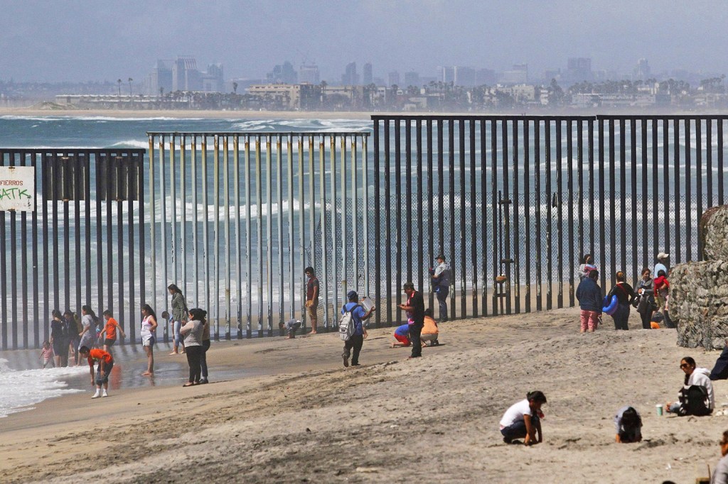 People are seen on the Mexican side of the U.S. border wall dividing a beach in Tijuana, Mexico, April 10, 2016. 