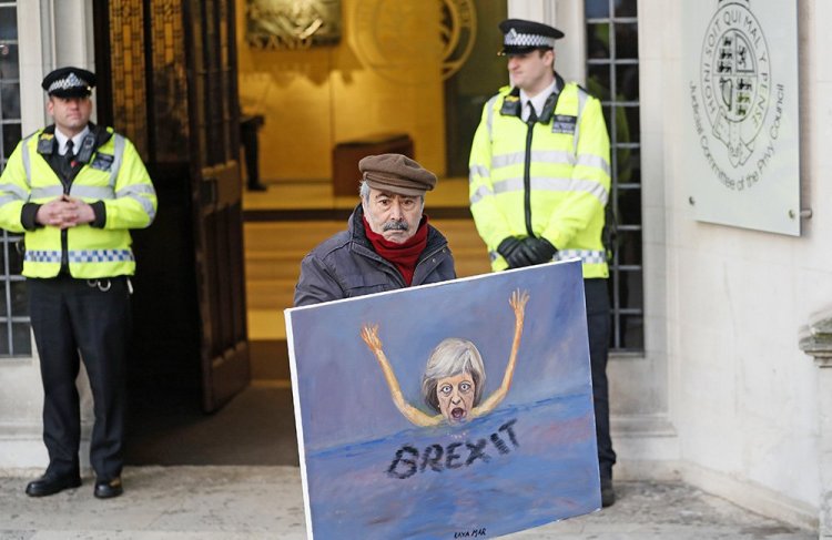 Artist Kaya Mar expresses his views with a painting of British Prime Minister Theresa May in front of the Supreme Court in London Tuesday. 