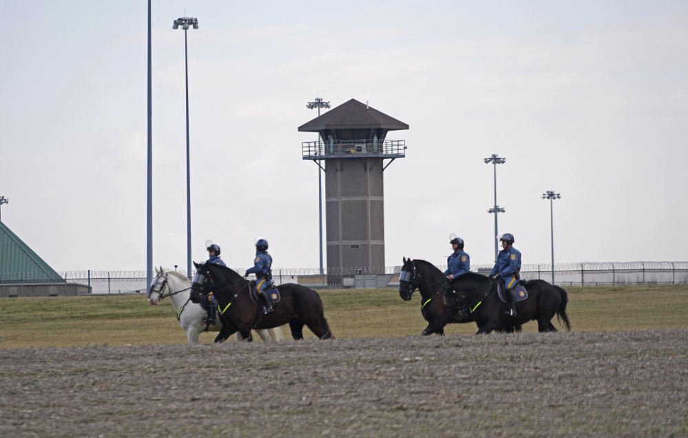 Mounted police patrol travel along Smyrna Landing Road alongside James T. Vaugh Corrections center Thursday in Smyrna, Del. Inmates used "sharp instruments" to assume control of the building Wednesday, taking three prison guards and a woman counselor hostage.