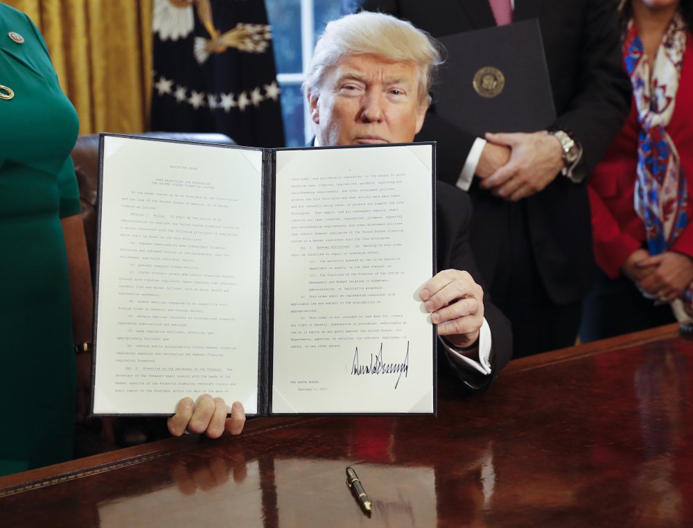 President Trump holds up an executive order he signed in the Oval Office of the White House in Washington on Friday. The executive order directs the Treasury secretary to review the 2010 Dodd-Frank financial oversight law, which reshaped financial regulation after 2008-2009 crisis.