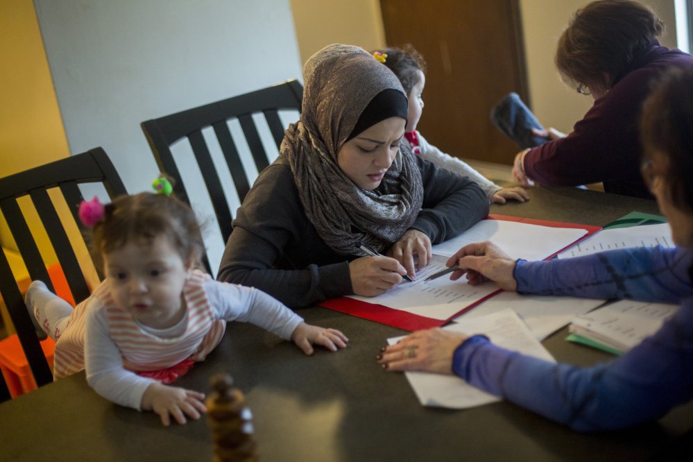 Fatema Aljasem studies English as her children, from left, Ahed, 2, and Shahaad, 3, sit nearby at their apartment in Omaha, Neb., last week.