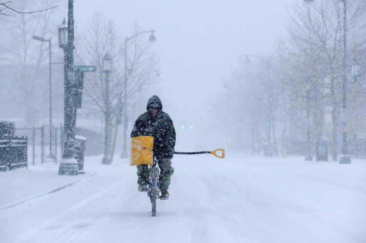 Angel Ares, of Hartford, bikes up Park Street on his way to shovel snow at buildings he takes care of in the Frog Hollow section of the city, as snow falls Thursday in Hartford, Conn.