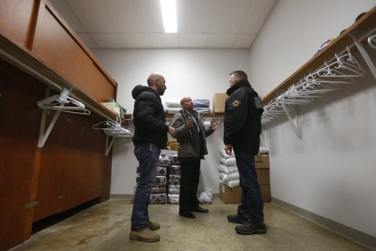 From left, Fadel Alshawwa, Jean Pierre Venegas, manager of the Manitoba Interfaith Immigration Council, and Bill Spanjer, municipal emergency coordinator for Emerson-Franklin, talk as they bring blankets and pillows into a community hall for refugees that may walk across the border in Emerson, Manitoba.