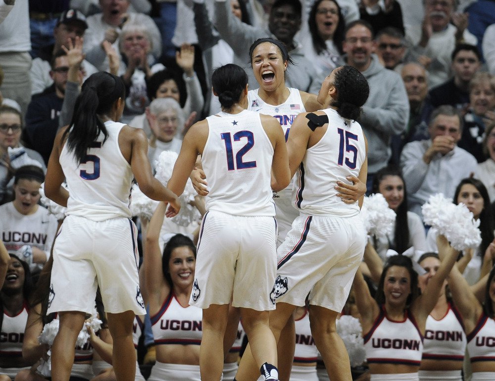 Connecticut's Napheesa Collier, center, reacts with teammates Crystal Dangerfield, left, Saniya Chong and Gabby Williams, right, in the second half of Monday night's game against South Carolina, the 100th consecutive win for the Huskies.