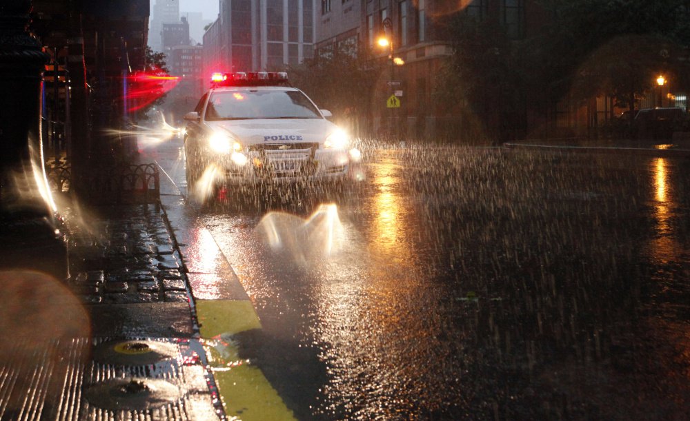 A New York City police cruiser flashes red lights in heavy rain as Hurricane Irene approaches in 2011.