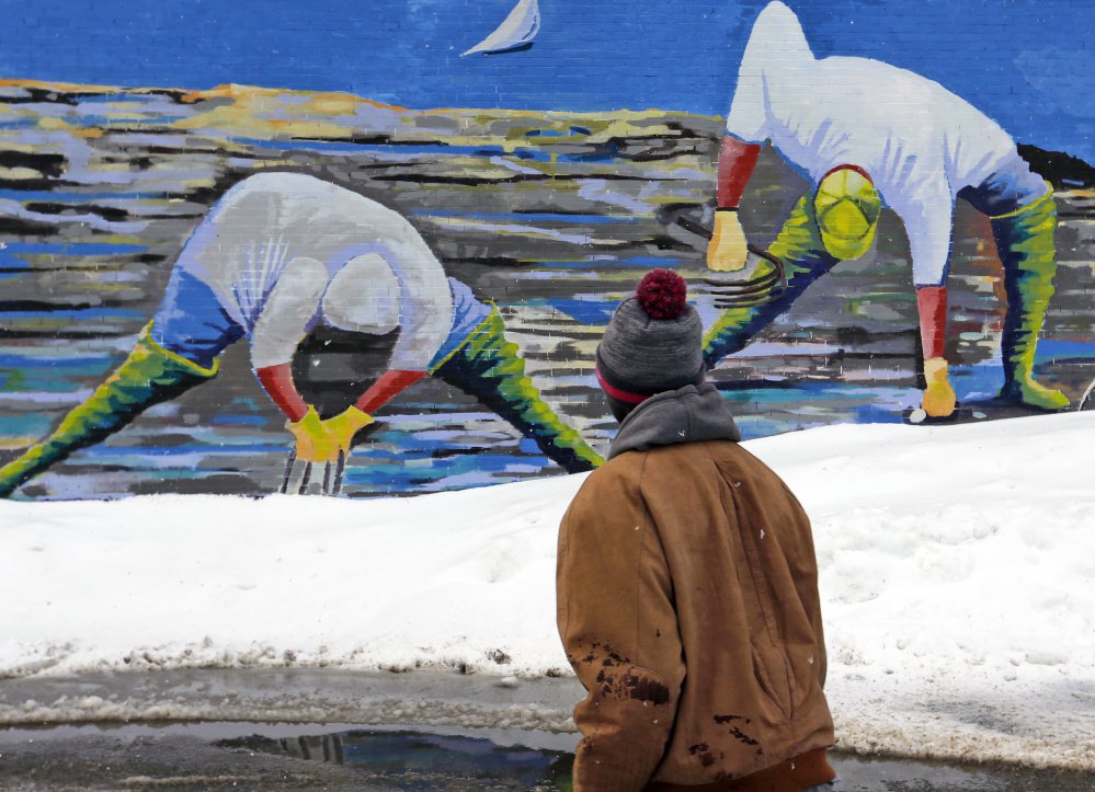 Two linf seeyse sdf fs yPORTLAND, ME - FEBRUARY 16: Clammers appear to be digging in snowpiles in artist Susan Bartlett Rice's mural as Larry Mundu, of Portland, walks past. (/Staff Photographer) Top photo A stop sign in Kennebunk is coated in wet snow on Thursday morning, February 16, 2016. Stop is what many Mainers may be thinking this morning as they wake up to another day of digging themselves out from more snow that fell overnight. (Staff Photo by Gregory Rec/Staff Photographer)
