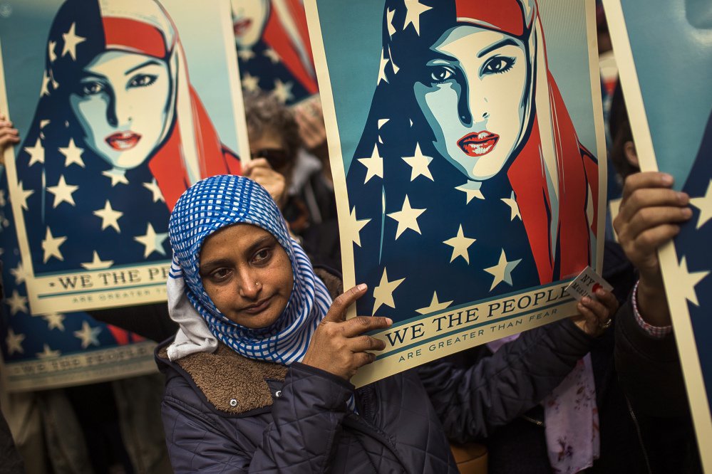 People carry posters during a rally against President Trump's executive order banning travel from seven Muslim-majority nations, in New York's Times Square, on Sunday.