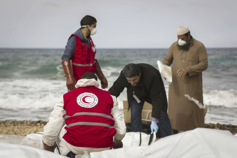 This photo provided by The International Federation of Red Cross and Red Crescent Societies, shows Libyan Red Crescent workers recovering bodies of people that washed ashore, near Zawiya, Libya.